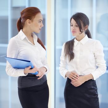 Two young beautiful businesswomen having meeting in modern office