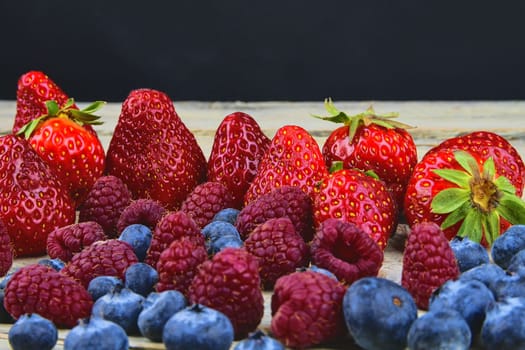 Healthy mixed fruit and ingredients with strawberry, raspberry, blueberry. Berries on rustic white wooden background. Free space for text. Copy space for banner.