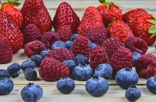 Healthy mixed fruit and ingredients with strawberry, raspberry, blueberry. Berries on rustic white wooden background. Close-up. Macro image.