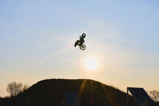 Freeride motocross rider making salto jump against the sun. 