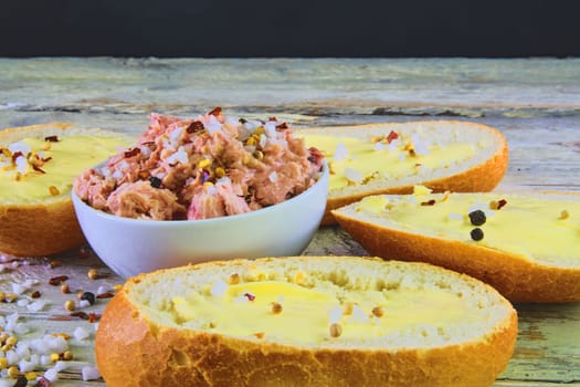 Slices of baguettes with butter and  fresh tuna with spices on wooden background. 