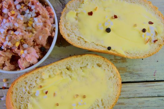 Slices of baguettes with butter and  fresh tuna with spices on wooden background. Top view. Flat design. 