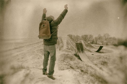 Middle age man jumping  in beautiful winter landscape . Man viewing on abandoned freestyle motocross ramps. Add color and oher filters