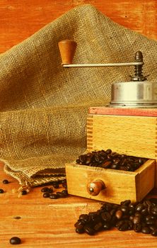 Vintage coffee mill and coffee beans on wooden background. 