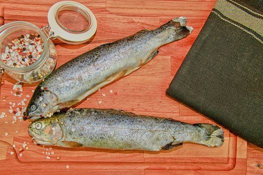 Fresh raw rainbow trouts with spices on wooden board. Healthy food and dieting concept. Close-up.