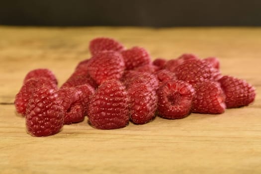 Red-fruited raspberries on wooden background. Raspberries background. Close-up.