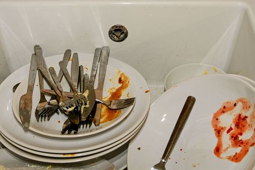 Dirty dishes and cutlery in a kitchen sink. Untidy dishes in the kitchen. 