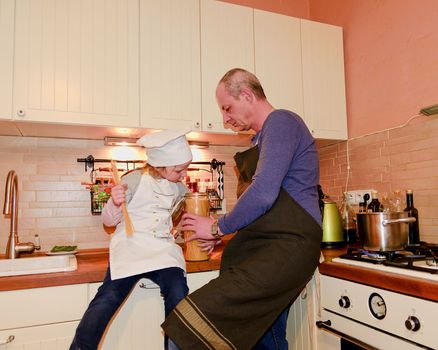 Daughter and father in the kitchen preparing spaghetti to dinner.