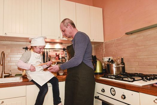 Daughter and father in the kitchen preparing spaghetti to dinner.