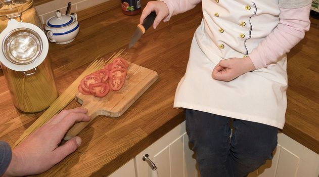 Daughter and father in the kitchen preparing spaghetti to dinner.