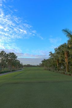 Freshly mowed green grass at dawn on a tropical golf course with a colorful sunrise sky.