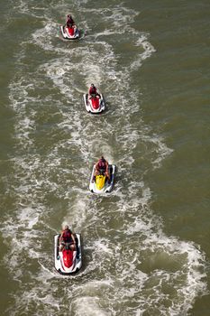 Group of jet skies zip along the ocean in a straight line, making waves in the ocean in the bay in front of Marco Island, Florida