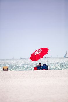 Blue sky over a red umbrella and white sand on Tigertail Beach on Marco Island, Florida