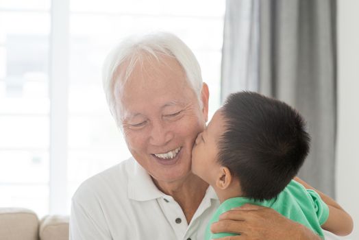 Portrait of happy Asian grandchild kissing grandfather at home, old senior retired people and child indoor lifestyle.