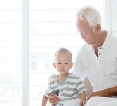 Portrait of Asian grandfather and grandchild at home, family indoor lifestyle.