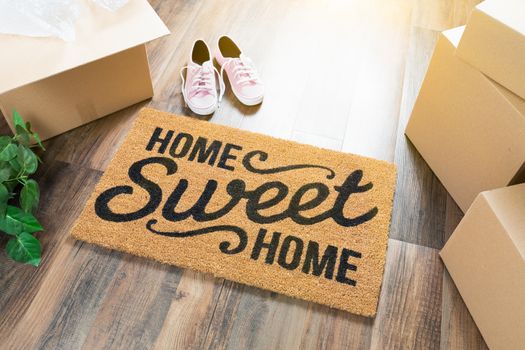 Home Sweet Home Welcome Mat, Moving Boxes, Pink Shoes and Plant on Hard Wood Floors.