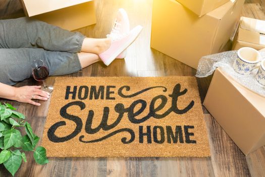 Woman Wearing Sweats Relaxing Near Home Sweet Home Welcome Mat, Moving Boxes and Plant.