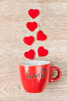 Red heart with red coffee cup on wooden background.