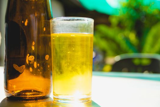 Whiskey or beer in a glass and on a table with nature background.