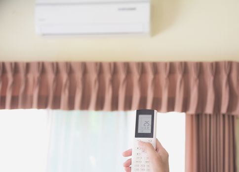 Hand holding remote control for open air conditioner in the room