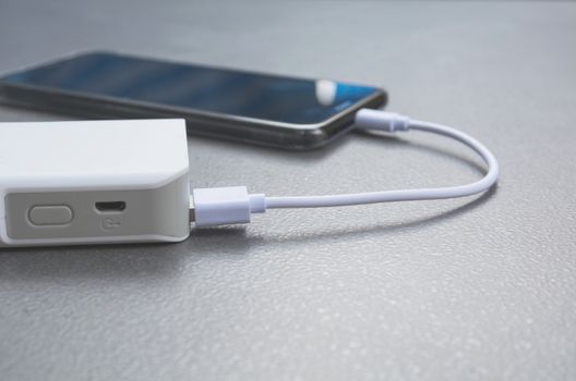 Mobile smart phones charging with power bank on desk.