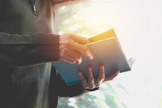 Woman holding blue book for read on nature background.