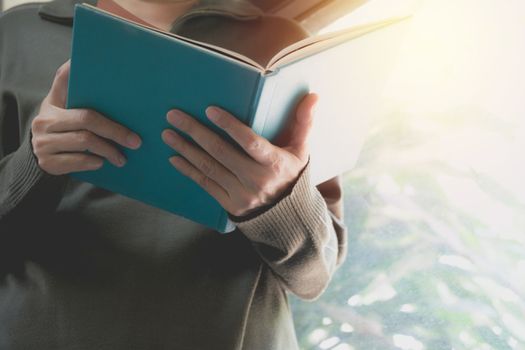 Woman holding blue book for read on nature background.