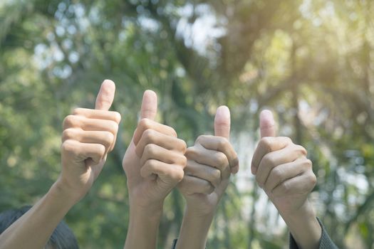 Hand of people shows the gesture of thumps up on nature background.