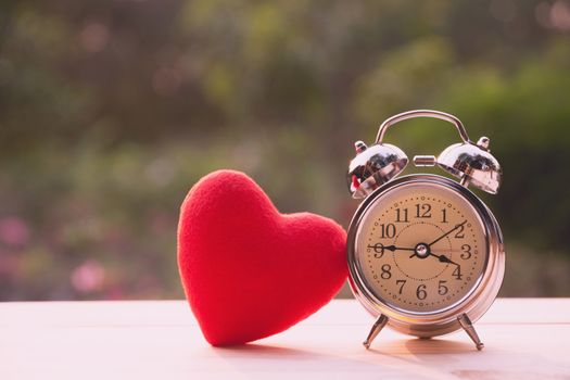 Red heart with alarm clock on wooden table for valentine day concept.