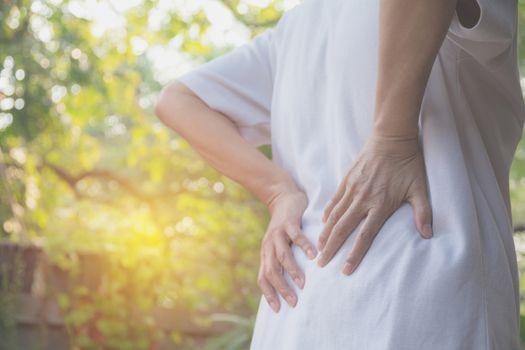 A woman suffering from backache, spinal injury and muscle issue problem at outdoor.