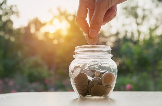 Hand of man holding coin and drop into the glass. Financial stock market in accounting market economy analysis.