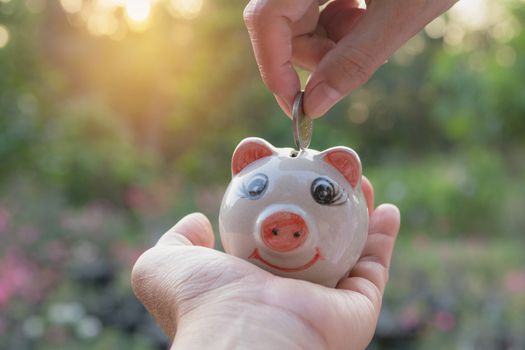 Hand of man holding coin and drop into the piggy bank. Financial stock market in accounting market economy analysis.