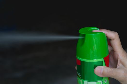 Hand holding mosquito spray. Human using mosquito spray from bottle.