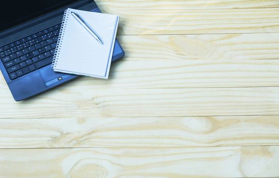 Top view of laptop with open book. Laptop with book open on wooden table background and copy space for text.