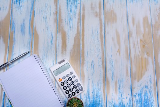 Top view of note book, pen and calculator on wooden table background with copy space.