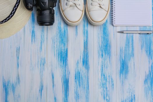 Topview of travel equipment,  sun hat, shoes and camera on wooden background. Copy space for creative design text and word.