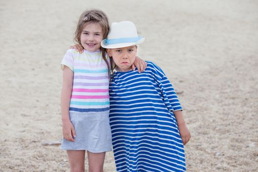 Couple of kids with funny faces, a boy and a girl around six, embracing each other.