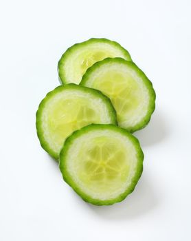 four slices of green cucumber on white background