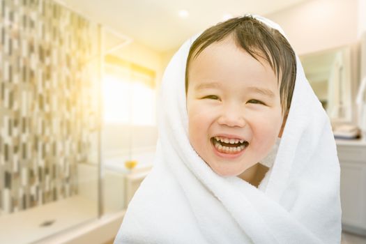 Happy Cute Mixed Race Chinese and Caucasian Boy In Bathroom Wrapped In A Towel.