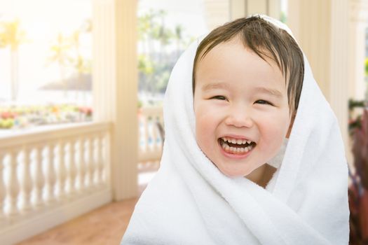 Happy Cute Mixed Race Chinese and Caucasian Boy On Tropical Patio Wrapped In A Towel.