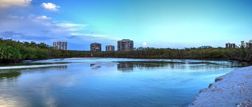 Moonrise over River leading to the ocean at Clam Pass at dusk in Naples, Florida