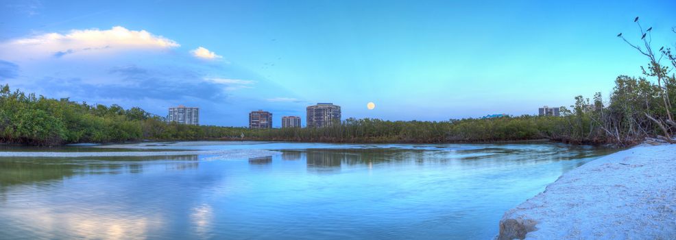 Moonrise over River leading to the ocean at Clam Pass at dusk in Naples, Florida