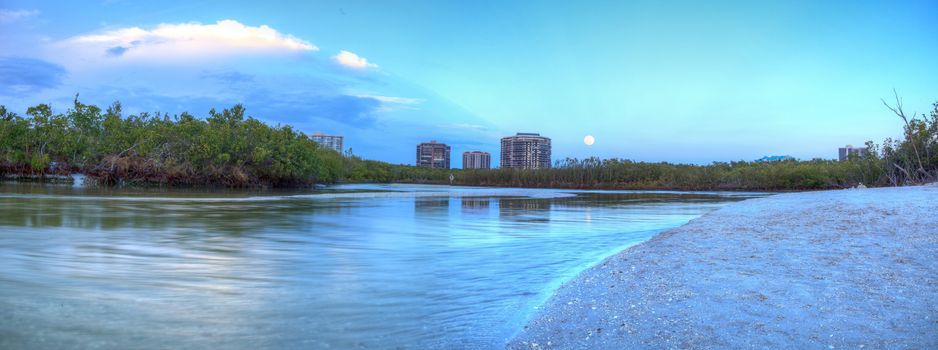 Moonrise over River leading to the ocean at Clam Pass at dusk in Naples, Florida