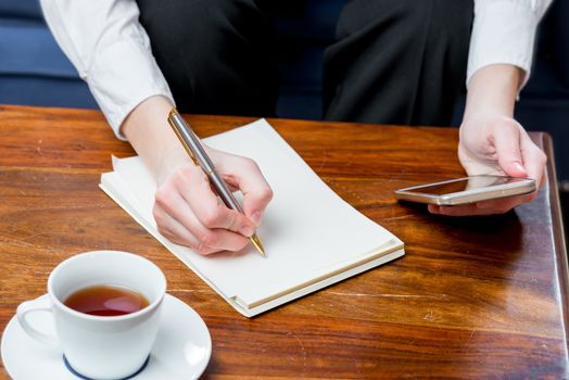 close-up of female hands record information in a notebook lying on a table