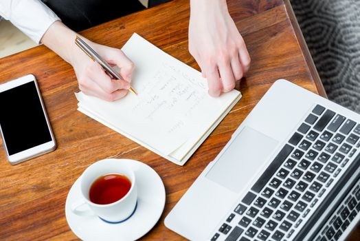 view of the hands at work, writing important information to the notebook