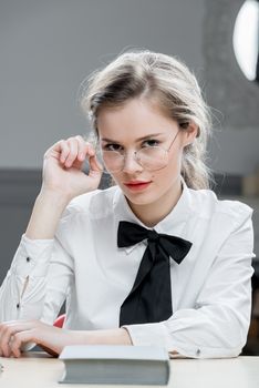 vertical portrait of businesswoman in stylish glasses sitting at table