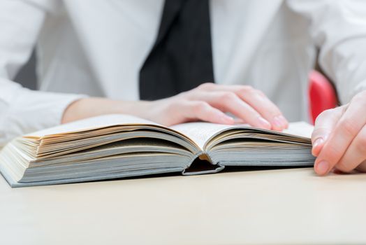 thick interesting book on a close-up table and women's hands