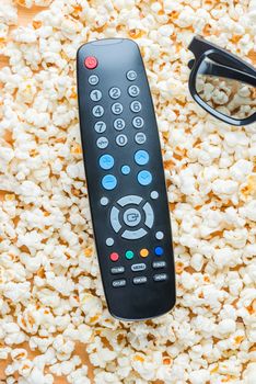 The vertical view of the remote from the TV and 3D glasses lie on the popcorn