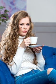 vertical portrait of a beautiful young woman with a cup of coffee on the couch