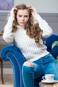 charming young girl sitting in living room on blue couch and posing